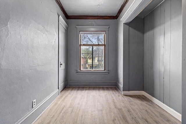 spare room with light wood-type flooring and ornamental molding