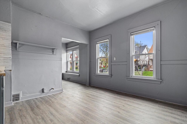 empty room with plenty of natural light and light hardwood / wood-style flooring