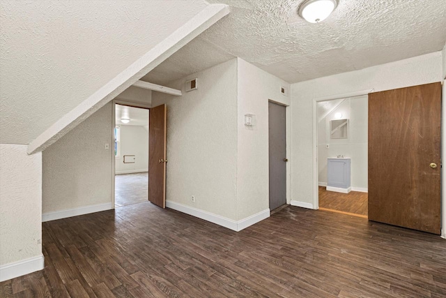 bonus room featuring dark wood-type flooring and a textured ceiling