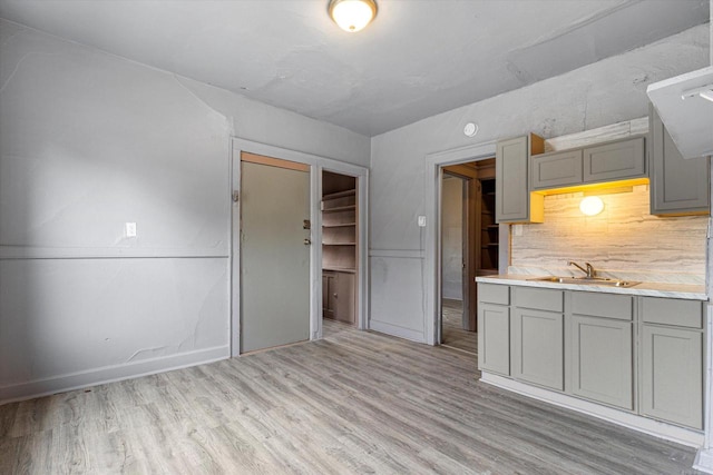 kitchen with gray cabinetry, light hardwood / wood-style floors, sink, and tasteful backsplash