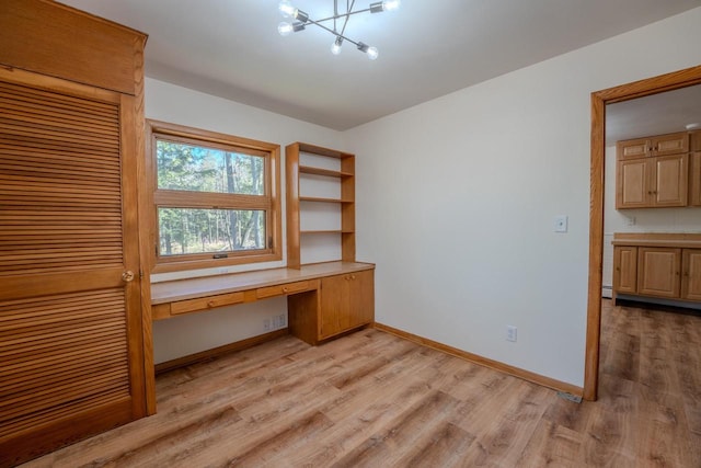 unfurnished office featuring built in desk and light wood-type flooring