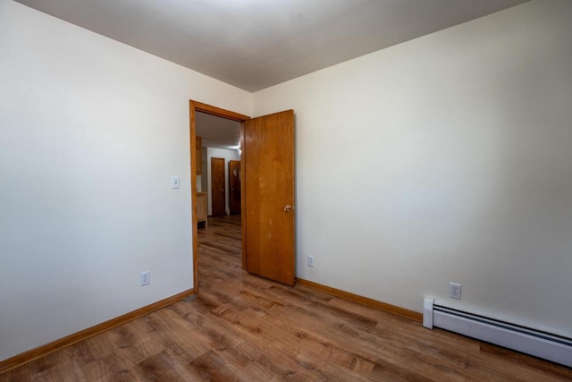 spare room featuring a baseboard heating unit and hardwood / wood-style floors