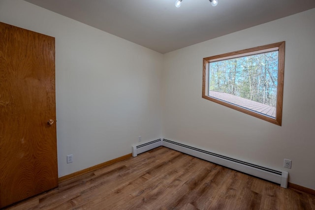 unfurnished room with a baseboard radiator and hardwood / wood-style flooring