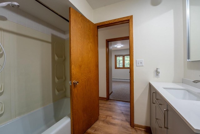 bathroom with hardwood / wood-style floors, washtub / shower combination, oversized vanity, and baseboard heating