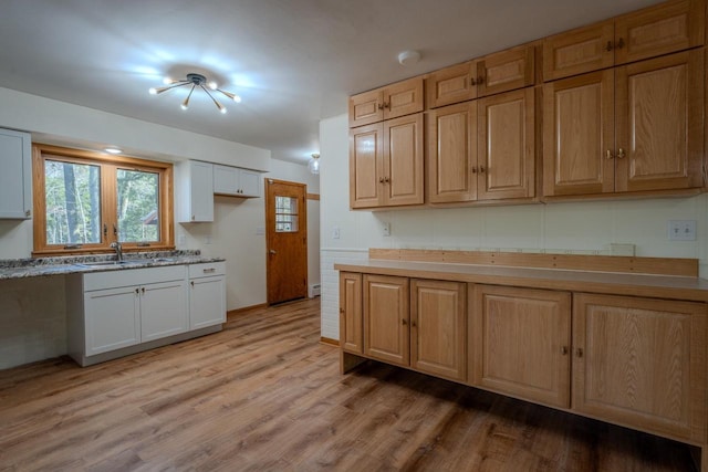 kitchen with white cabinets, wood-type flooring, and sink