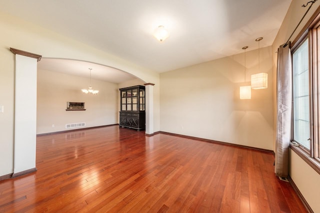 unfurnished living room with plenty of natural light, wood-type flooring, and a notable chandelier