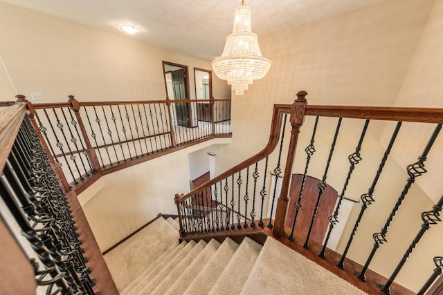 stairway with a notable chandelier and carpet flooring