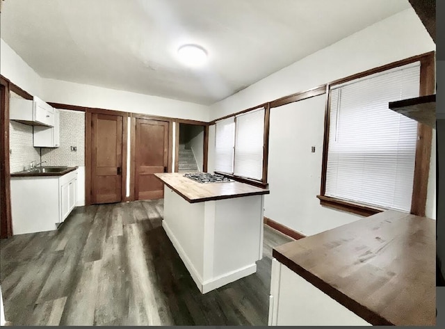 kitchen with decorative backsplash, dark hardwood / wood-style floors, white cabinetry, and stainless steel gas cooktop