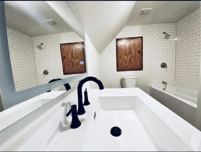 bathroom featuring tiled shower / bath combo and toilet