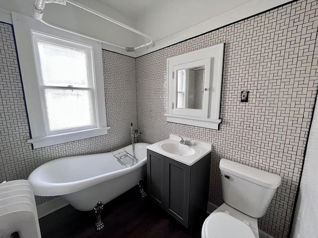 bathroom with radiator, vanity, a bath, tile walls, and toilet