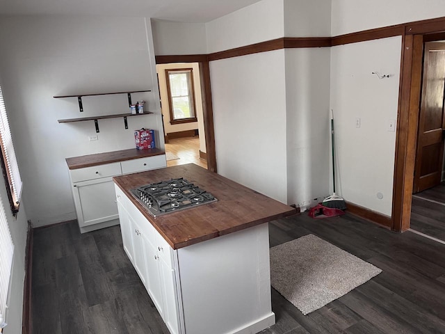 kitchen with wood counters, stainless steel gas cooktop, dark wood-type flooring, white cabinets, and a center island