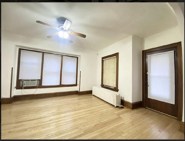 unfurnished room featuring radiator, ceiling fan, cooling unit, and light wood-type flooring