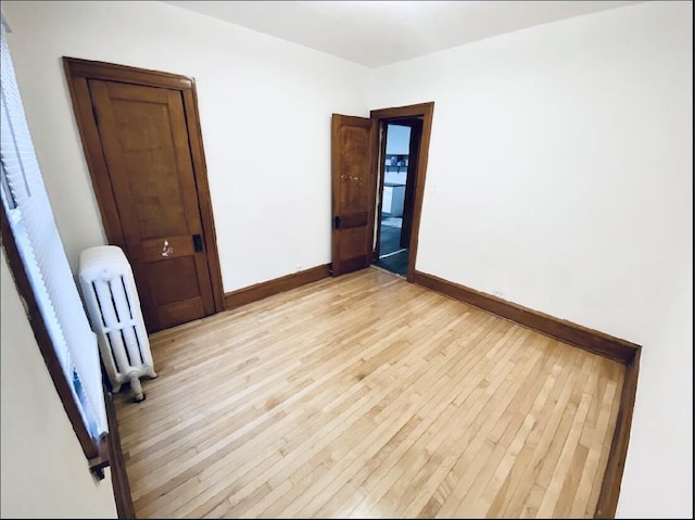 spare room featuring radiator heating unit and light wood-type flooring