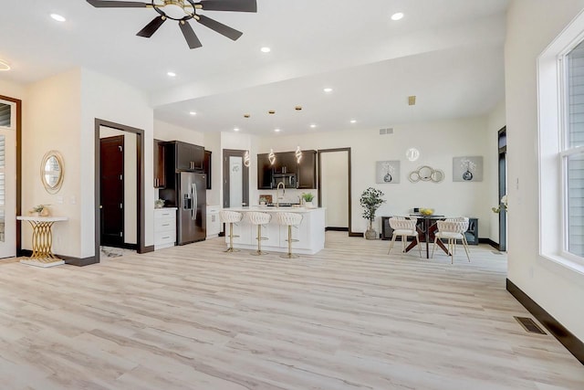 living room with sink, light hardwood / wood-style floors, and ceiling fan