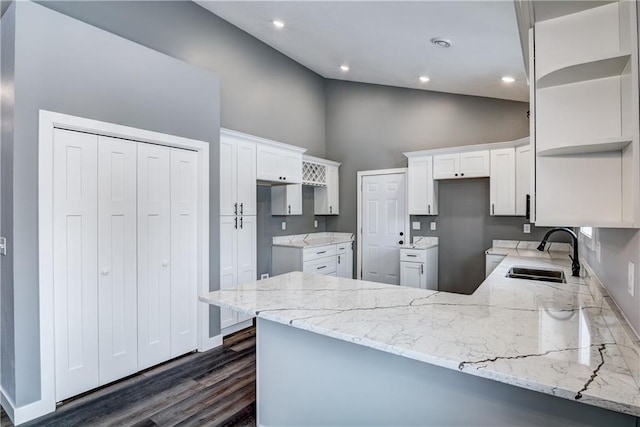 kitchen featuring high vaulted ceiling, sink, white cabinets, dark wood-type flooring, and kitchen peninsula