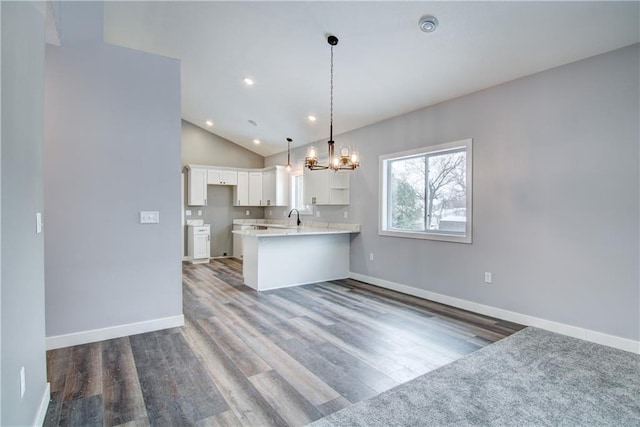 kitchen with wood-type flooring, hanging light fixtures, white cabinetry, kitchen peninsula, and lofted ceiling