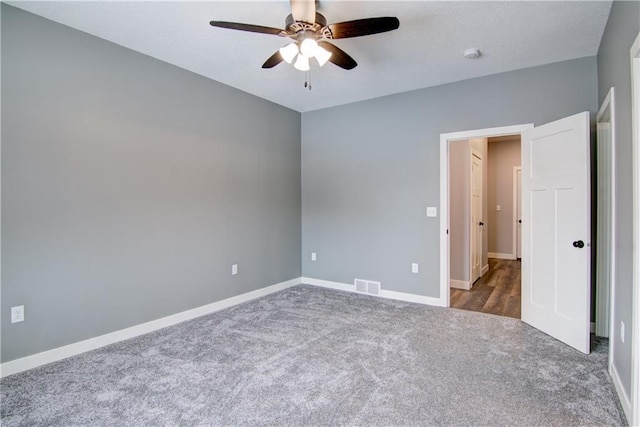 empty room with dark colored carpet and ceiling fan