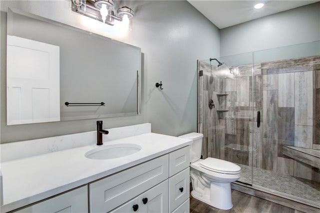 bathroom featuring wood-type flooring, toilet, oversized vanity, and a shower with shower door