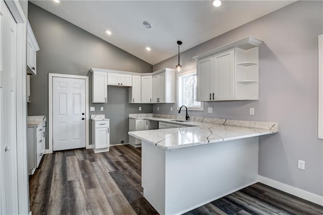 kitchen featuring dark wood-type flooring, hanging light fixtures, lofted ceiling, kitchen peninsula, and light stone countertops