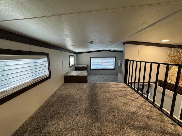 corridor featuring lofted ceiling, dark carpet, and a textured ceiling