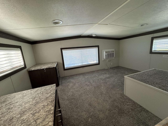 unfurnished bedroom with dark colored carpet, a textured ceiling, a wall mounted AC, and lofted ceiling