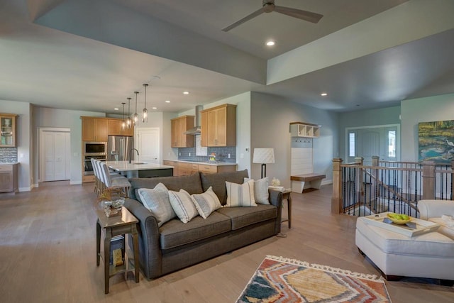 living room featuring sink, ceiling fan, and light wood-type flooring