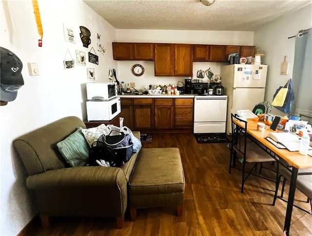 kitchen with a textured ceiling, white appliances, and dark wood-type flooring