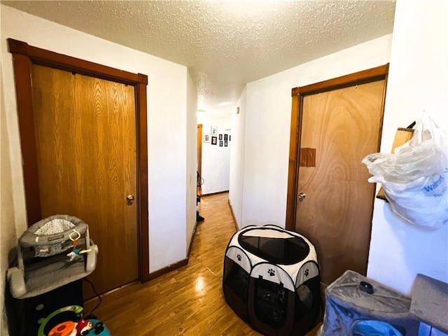 hallway with a textured ceiling and hardwood / wood-style flooring