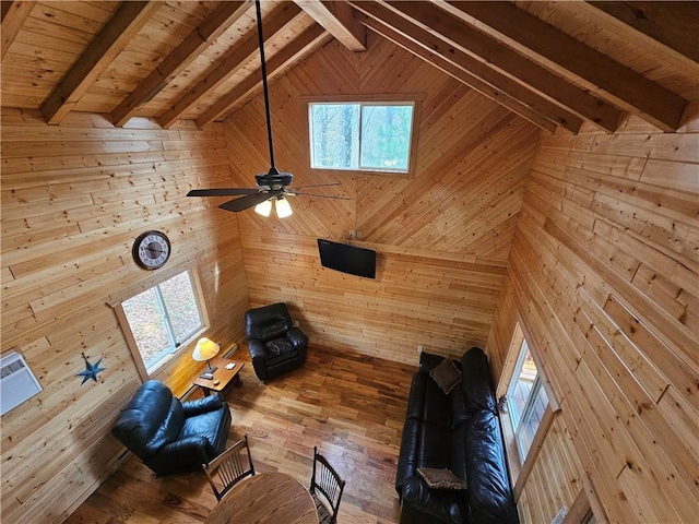 unfurnished living room with wooden ceiling, beam ceiling, ceiling fan, and wooden walls