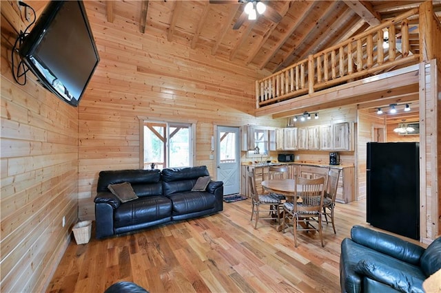 living room featuring high vaulted ceiling, light wood-type flooring, and wooden walls