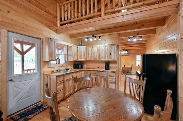 kitchen with beamed ceiling, light hardwood / wood-style flooring, light brown cabinets, black appliances, and sink