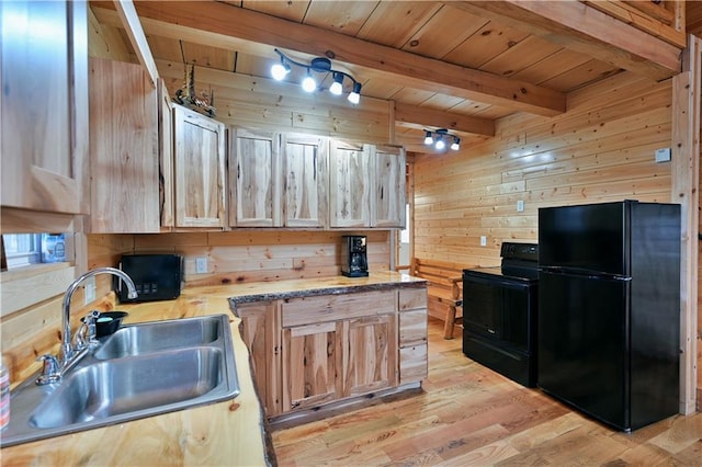 kitchen featuring beamed ceiling, sink, light wood-type flooring, black appliances, and wood walls