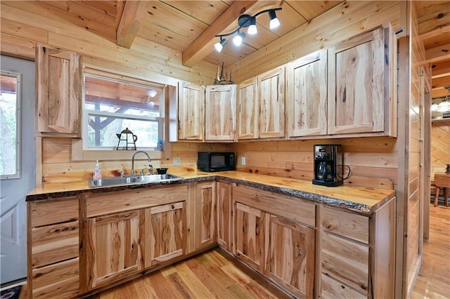 kitchen with wood walls, light hardwood / wood-style floors, beamed ceiling, wood ceiling, and sink