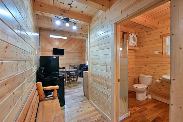 bathroom with wooden walls, beamed ceiling, hardwood / wood-style flooring, wood ceiling, and toilet