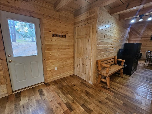 doorway featuring wood-type flooring, wood walls, and beam ceiling