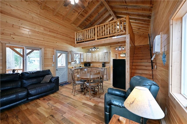 living room with beamed ceiling, high vaulted ceiling, light hardwood / wood-style floors, wood ceiling, and wood walls