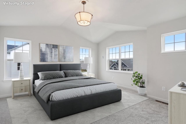 bedroom featuring lofted ceiling, light carpet, and multiple windows