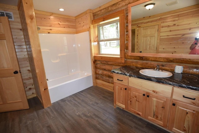 bathroom with  shower combination, hardwood / wood-style floors, wood walls, and vanity