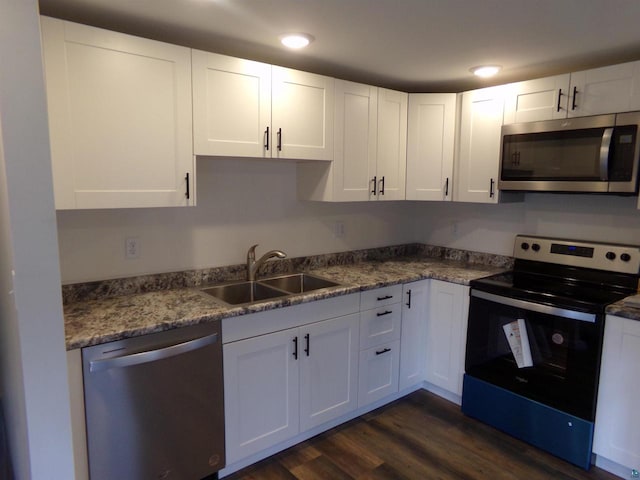 kitchen featuring white cabinets, dark hardwood / wood-style floors, stainless steel appliances, stone countertops, and sink