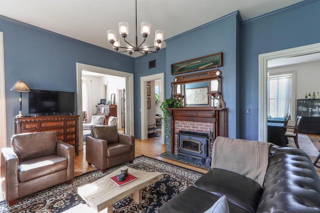 living room featuring crown molding, a notable chandelier, hardwood / wood-style floors, and a brick fireplace