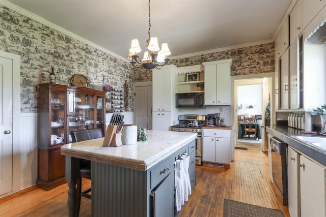 kitchen featuring hanging light fixtures, gas stove, hardwood / wood-style floors, a notable chandelier, and dishwasher