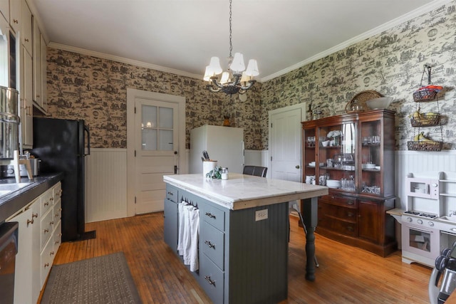 kitchen featuring black fridge, hardwood / wood-style flooring, pendant lighting, a breakfast bar, and a notable chandelier