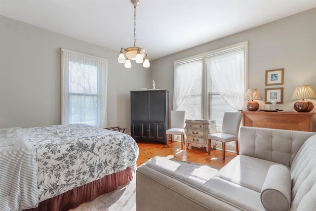 bedroom with multiple windows, light hardwood / wood-style floors, and a chandelier