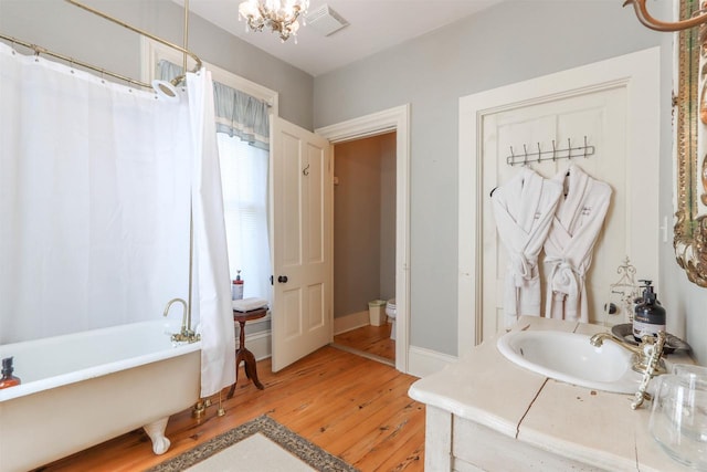 bathroom featuring a bath, sink, hardwood / wood-style floors, and toilet