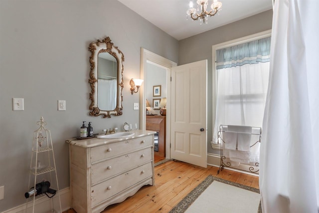 bathroom with wood-type flooring, vanity, and an inviting chandelier