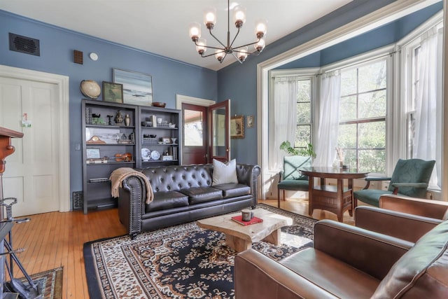 living room with crown molding, wood-type flooring, and an inviting chandelier