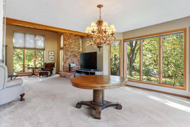 carpeted living room featuring a fireplace and an inviting chandelier