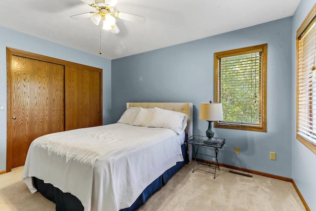 carpeted bedroom with a closet, ceiling fan, and multiple windows