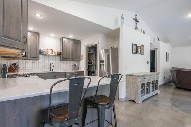 kitchen with a kitchen breakfast bar, kitchen peninsula, stainless steel appliances, backsplash, and sink