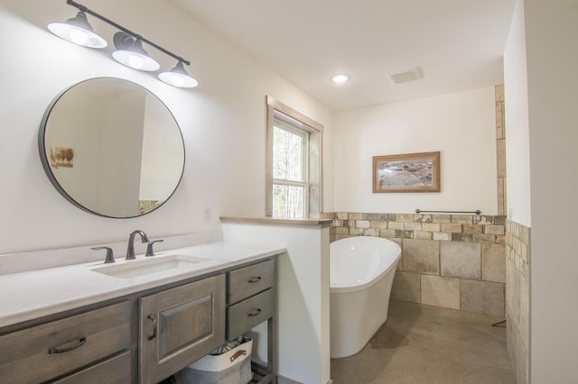 bathroom with concrete flooring, vanity, and a tub